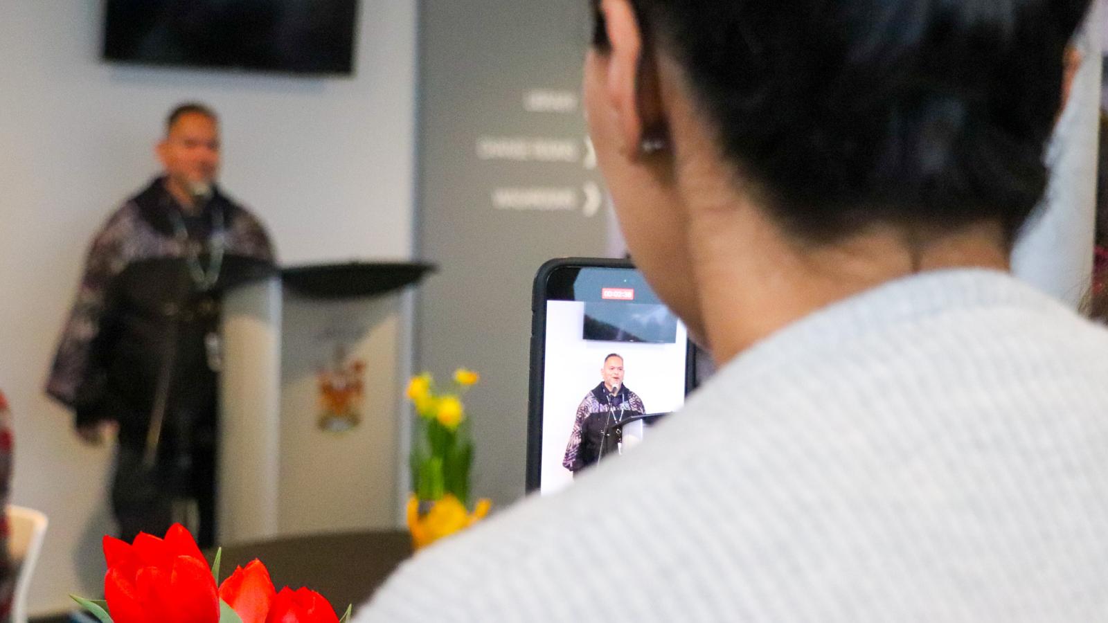 Woman recording Kwantlen Indigenous Knowledge Keeper, Dennis Leon's welcoming remarks