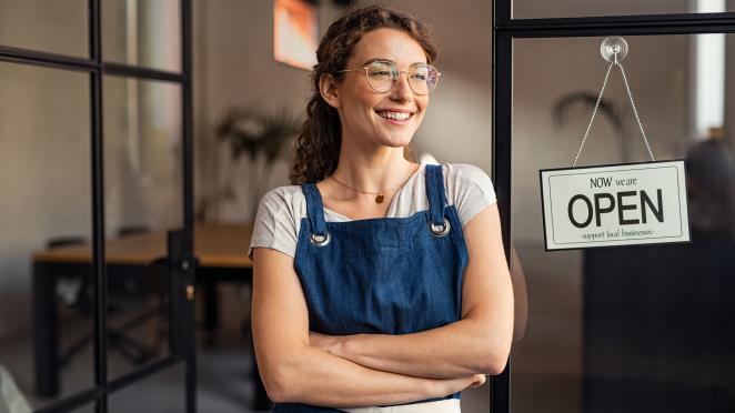 female business owner standing in the door way of her open business