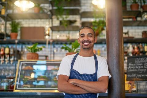 smiling man standing by checkout of coffee shop business