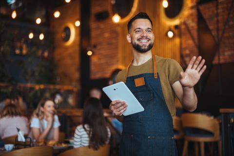 Smiling Waiter Greeting Customers in a Cozy Langley City Restaurant Setting