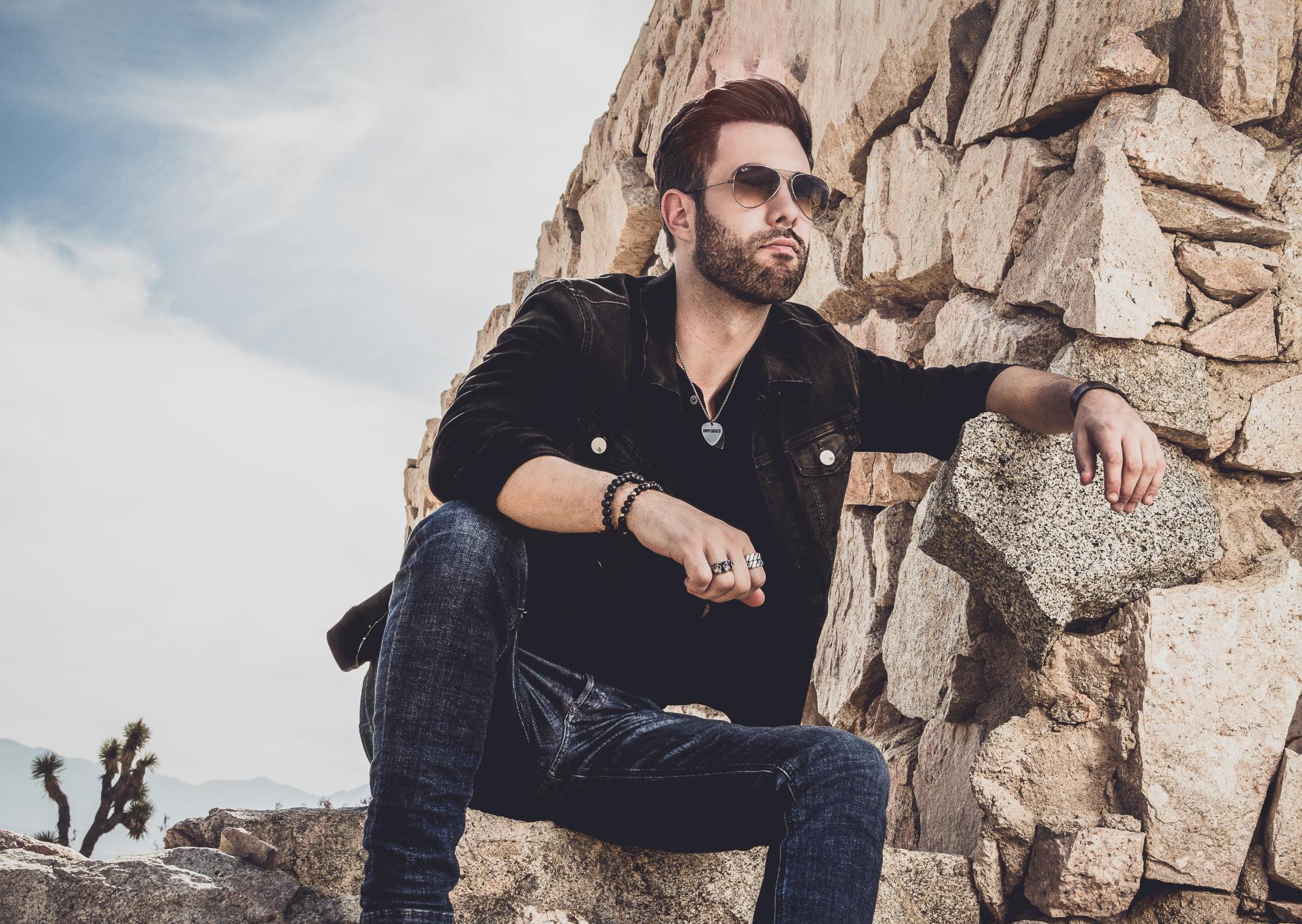 One male sitting against a rock wall; musician Dave Hartney