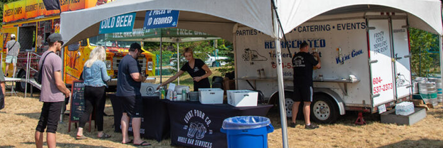 People standing in a line, waiting to purchase beer from a vendor at an outdoor festival.