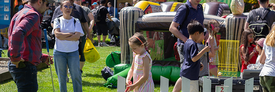 Families and Kids playing mini golf and jumping on inflatables at an outdoor festival