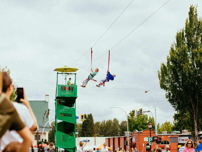 Two participants on a zip line at an outdoor event.